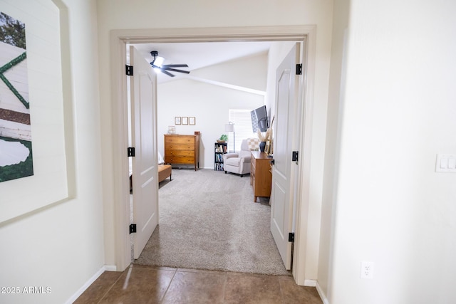 hall featuring lofted ceiling, tile patterned flooring, baseboards, and carpet flooring