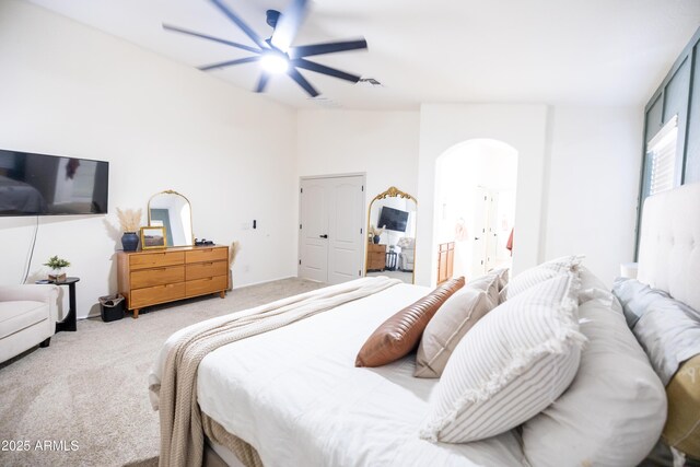 carpeted bedroom featuring lofted ceiling, arched walkways, a ceiling fan, and ensuite bathroom