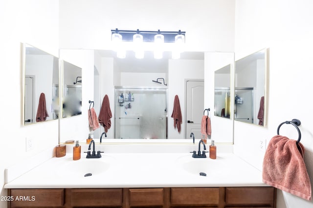 full bathroom with double vanity, a shower stall, and a sink