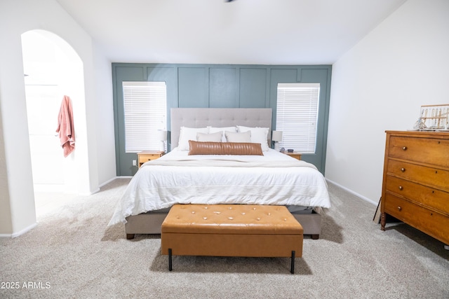 carpeted bedroom featuring baseboards and arched walkways