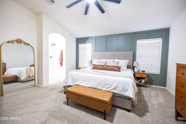 carpeted bedroom featuring a ceiling fan, arched walkways, vaulted ceiling, and baseboards