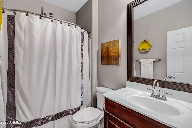 bathroom with toilet, vanity, and walk in shower