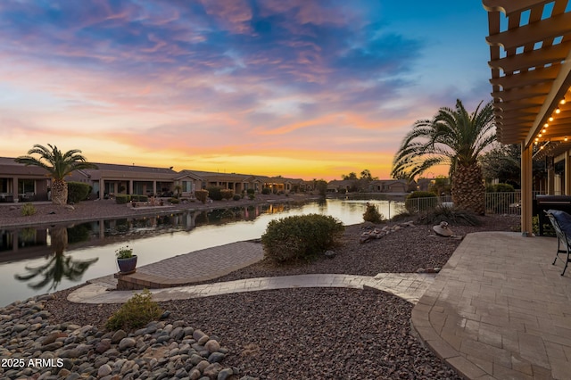 yard at dusk featuring a water view and a patio