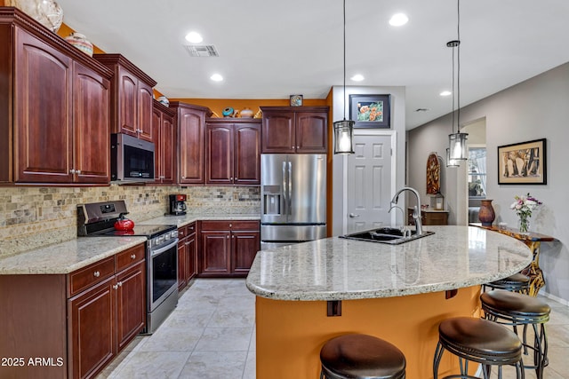 kitchen with stainless steel appliances, a kitchen bar, and a center island with sink