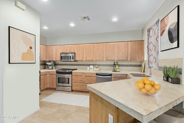 kitchen featuring stainless steel appliances, a peninsula, a sink, visible vents, and light countertops