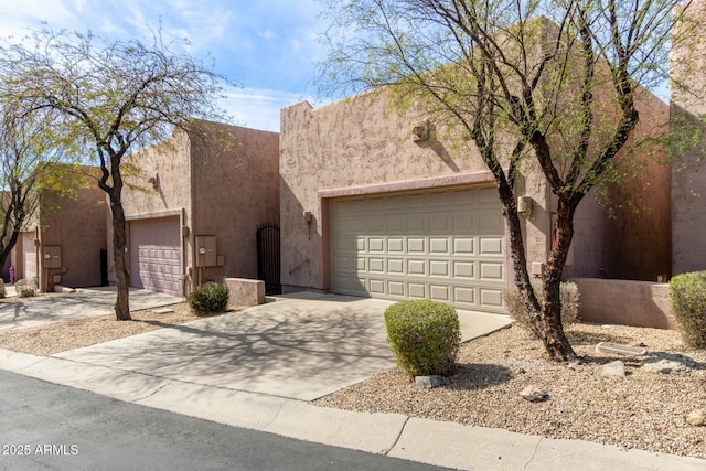 adobe home featuring a garage, concrete driveway, and stucco siding