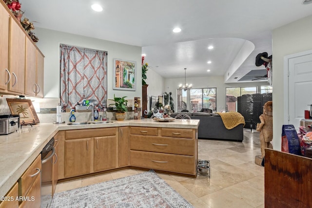 kitchen with open floor plan, a peninsula, an inviting chandelier, light countertops, and a sink