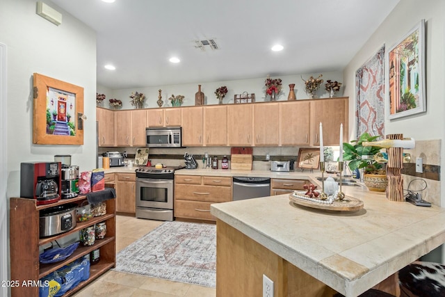 kitchen with recessed lighting, a peninsula, a sink, visible vents, and appliances with stainless steel finishes