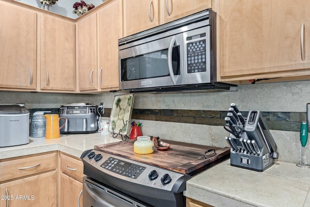 kitchen featuring light brown cabinets, stainless steel appliances, backsplash, and light countertops