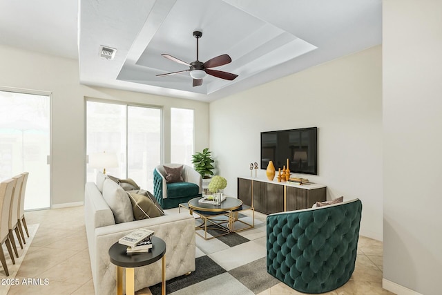 living room with light tile patterned floors, baseboards, visible vents, and a raised ceiling