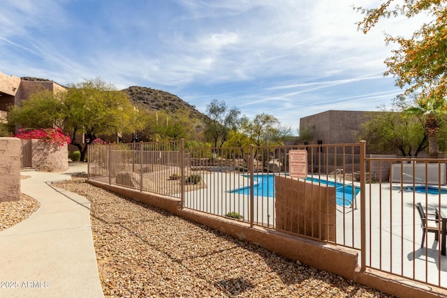 pool featuring a mountain view, a patio, and fence