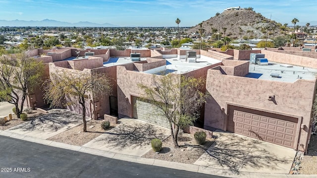 exterior space featuring concrete driveway, a mountain view, and stucco siding