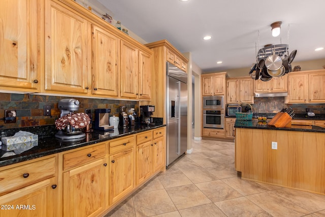 kitchen featuring dark stone counters, decorative backsplash, built in appliances, and light tile patterned floors