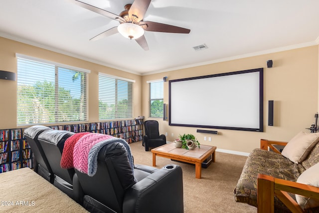 carpeted cinema room with ceiling fan and crown molding