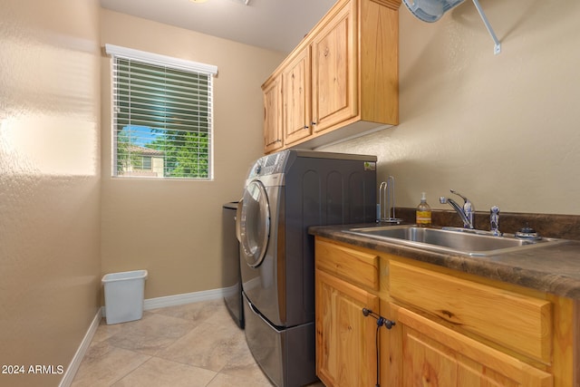 laundry room with light tile patterned flooring, sink, washing machine and clothes dryer, and cabinets