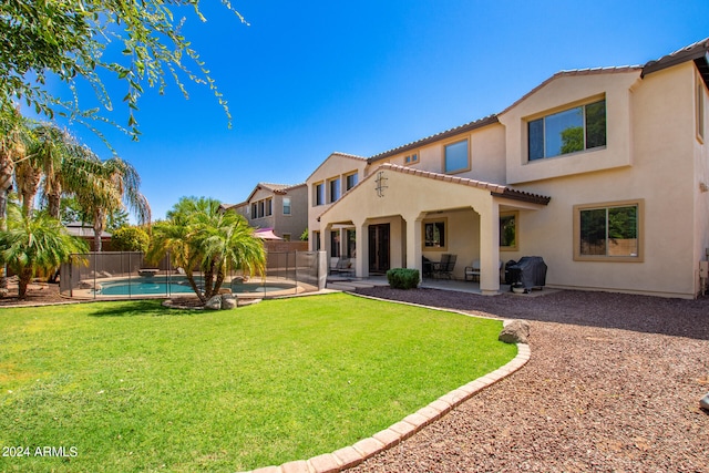 back of property with a lawn, a fenced in pool, and a patio area