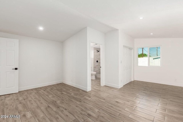 spare room featuring vaulted ceiling and light wood-type flooring