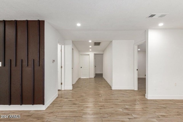 hall with a textured ceiling and light hardwood / wood-style floors