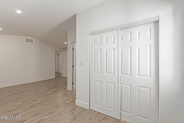 corridor featuring light wood-type flooring and lofted ceiling