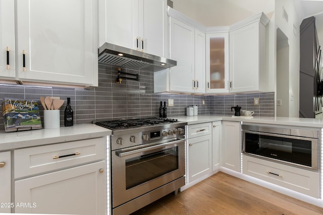 8419 E Rancho Vista Dr, Scottsdale, AZ 85251 - kitchen featuring light wood-style floors, white cabinetry, exhaust hood, backsplash, and stainless steel range with gas stovetop