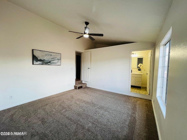 unfurnished bedroom with vaulted ceiling, ensuite bath, ceiling fan, and carpet flooring