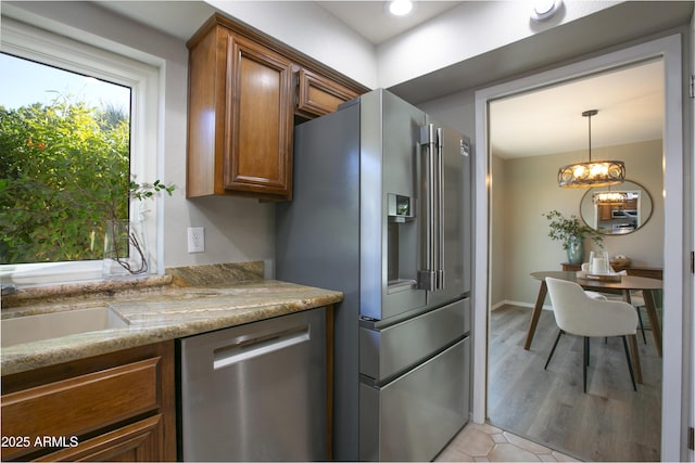 kitchen featuring light stone countertops, a notable chandelier, stainless steel appliances, and pendant lighting