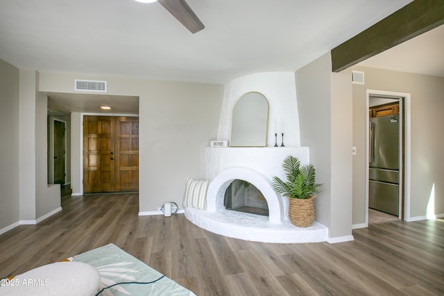 living room featuring ceiling fan, hardwood / wood-style floors, and beamed ceiling