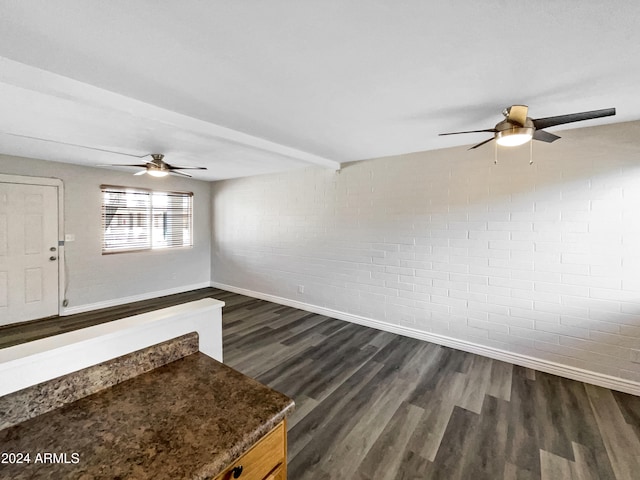 empty room featuring beamed ceiling, brick wall, and dark hardwood / wood-style floors