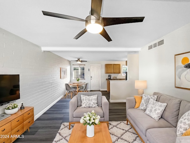 living room with dark wood-type flooring, a healthy amount of sunlight, ceiling fan, and brick wall