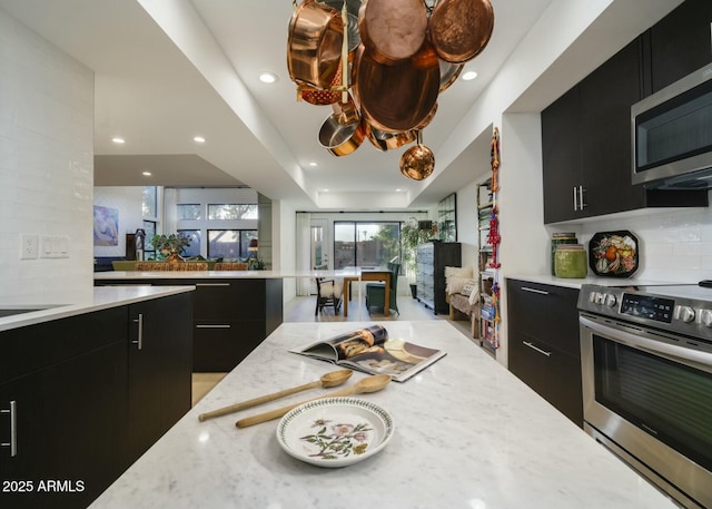 kitchen featuring appliances with stainless steel finishes, light stone counters, and a tray ceiling