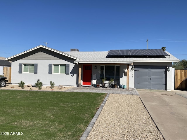 ranch-style home featuring driveway, solar panels, an attached garage, fence, and a front yard