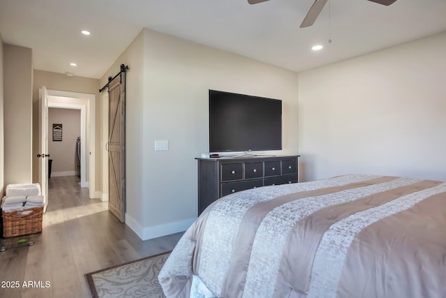 bedroom with a barn door, baseboards, ceiling fan, wood finished floors, and recessed lighting