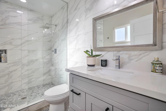 full bathroom featuring tiled shower, vanity, toilet, and tile walls