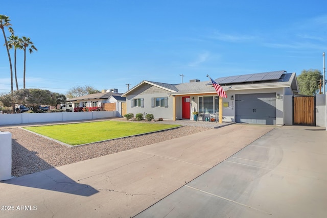 ranch-style house with an attached garage, roof mounted solar panels, fence, and a front yard