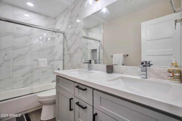 bathroom with enclosed tub / shower combo, double vanity, a sink, and toilet