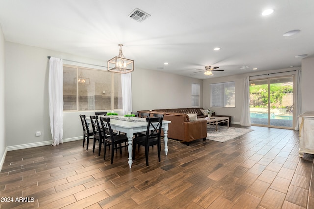 dining area featuring ceiling fan with notable chandelier and dark hardwood / wood-style flooring