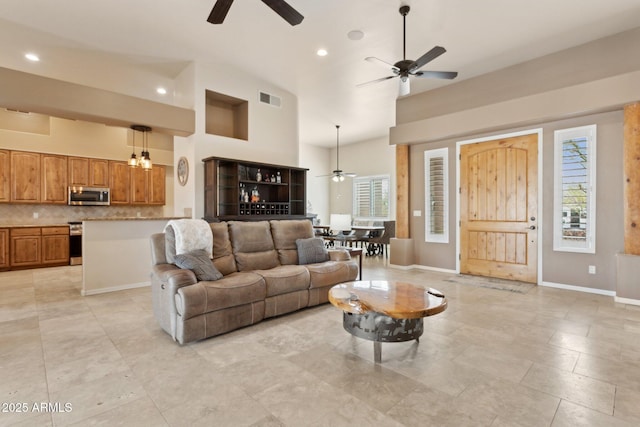 living room featuring baseboards, a healthy amount of sunlight, visible vents, and high vaulted ceiling