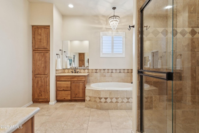 full bath with vanity, a stall shower, tile patterned flooring, a garden tub, and a notable chandelier