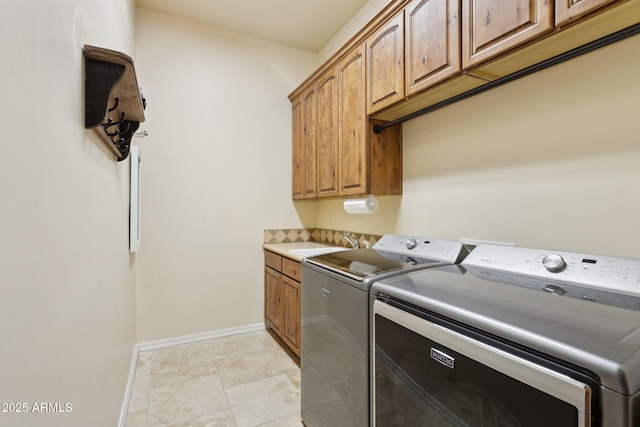 laundry room featuring baseboards, washing machine and dryer, light tile patterned floors, cabinet space, and a sink