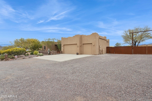 view of home's exterior featuring concrete driveway, fence, a garage, and stucco siding