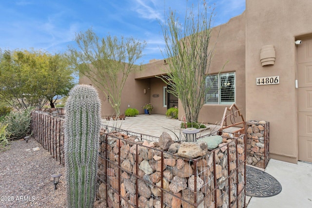 exterior space with stucco siding, fence, and a patio area