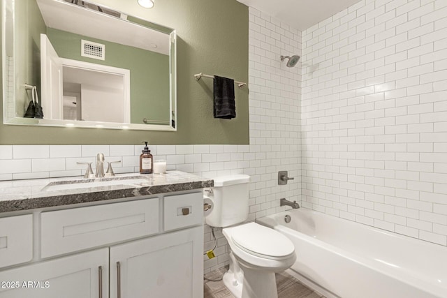 full bathroom featuring vanity, toilet, tile walls, bathing tub / shower combination, and visible vents