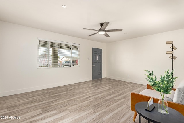 living room with baseboards, ceiling fan, and light wood-style flooring