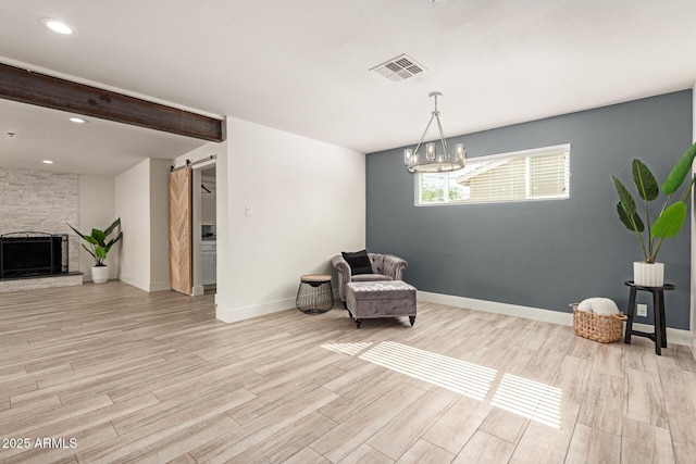unfurnished room with baseboards, visible vents, a barn door, and light wood finished floors