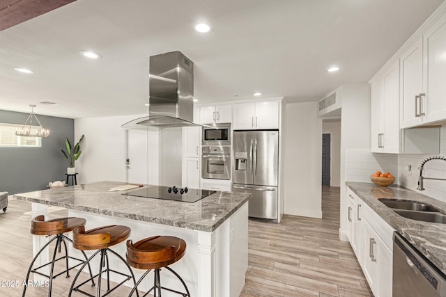 kitchen with a kitchen island, island range hood, appliances with stainless steel finishes, light stone countertops, and a sink