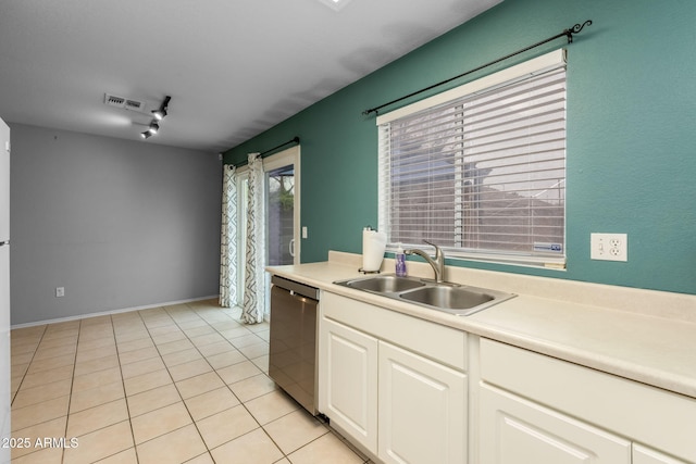 kitchen with sink, rail lighting, dishwasher, white cabinets, and light tile patterned flooring