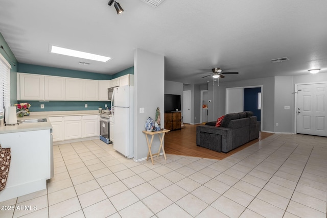 kitchen featuring sink, white cabinetry, stainless steel range with electric stovetop, white refrigerator, and light tile patterned flooring