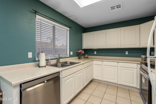 kitchen with stainless steel appliances, light tile patterned flooring, sink, and white cabinets