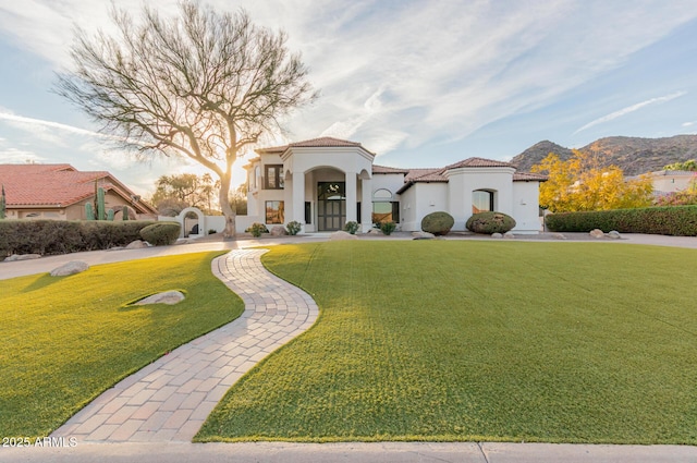 mediterranean / spanish-style home featuring stucco siding, a tiled roof, a mountain view, and a front yard