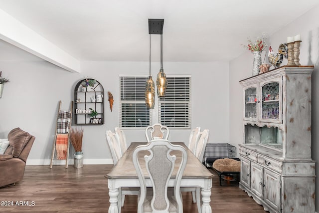 dining space featuring dark wood-type flooring, a notable chandelier, and baseboards